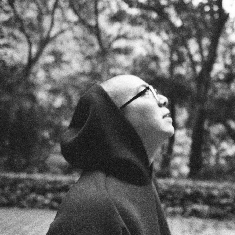 Peter in a hooded jacket, looking up at the trees, shot on black and white film